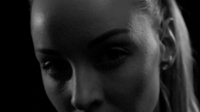 Close up of face of young woman in dark studio turning her head from side to side and looking away