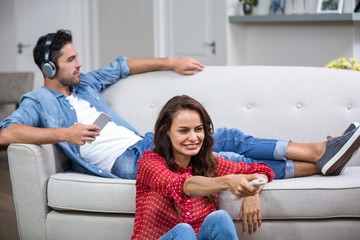 Man listening to music while woman changing channel 