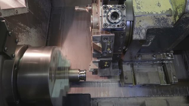 Closer look of the turning machine with drill bits scraping and making holes on the metal tubes from the other machine