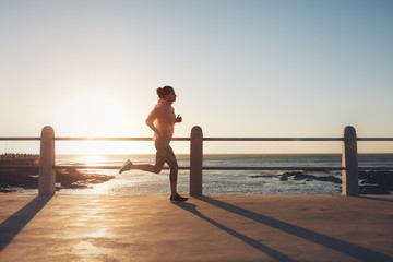 Fit and young woman running on the seaside road