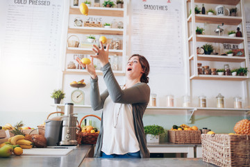 Young woman juggling with lemon at juice bar