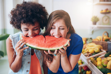 Two young woman eating watermelon and having fun - obrazy, fototapety, plakaty