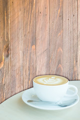 Hot cup of coffee latte on wooden background