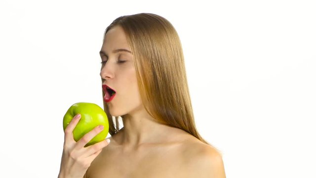 Female with braces on her teeth eating green apple and smile. White. Closeup
