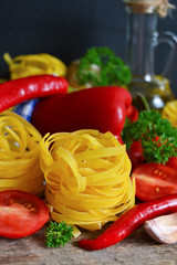 raw pasta with tomatoes and peppers on a black background