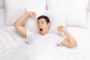 Rested man waking up in a bed