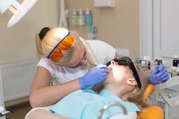 Woman dentist in mask treating her patient