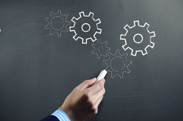 Man drawing gears on blackboard