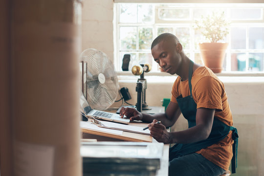 African small business owner working seriously at his studio desktop