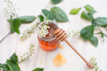 Honey with wooden honey dipper and glass jar and flowers. Top view.