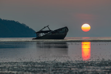 abandon wreck boat and sun rising sky at phuket southern of thai