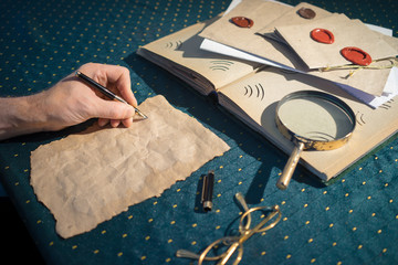 Pure gold leaf and a pen in the hand of a man who begins to write