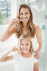 Portrait of smiling mother and daughter brushing teeth 