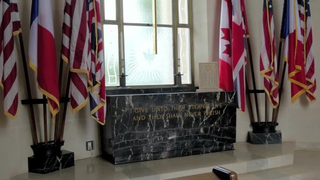 Small flaglets on the window of the room from the building found inside the cemetery in Normandy