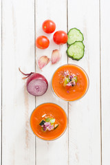 Gazpacho soup and ingredients on white wooden background

