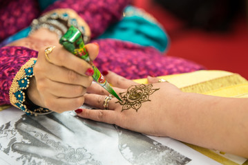 Applying henna tattoo on woman's hand (mehndi)