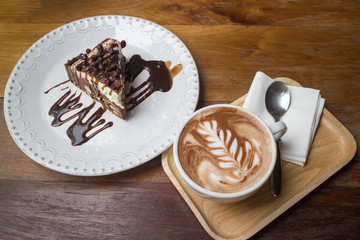 Sweet chocolate ship cake with syrup and hot art of coffee on the dish