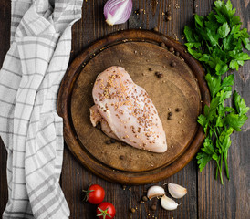 Fresh, chicken fillet with spices, wooden cutting board, top view.