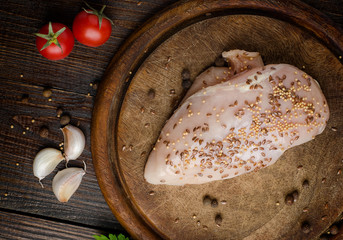 Chicken fillet, tomatoes, garlic, spices, on cutting board, top view.