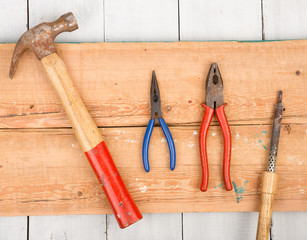 Set of old tools - hammer, pliers and soldering Iron on wooden background