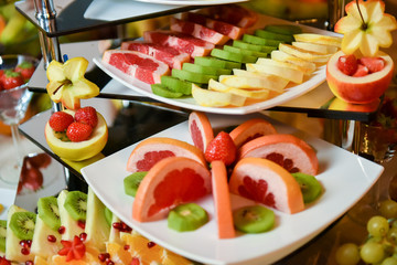 Plates with different type of fruits: strawberry, pineapple, orange, kiwi