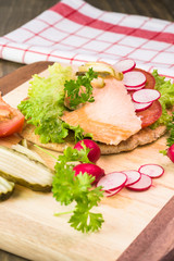 Fototapeta na wymiar Fresh homemade pita sandwich with hot smoked salmon, letuce and vegetables.