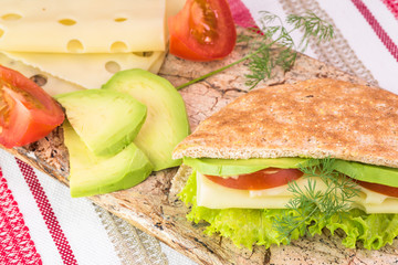 Pita pocket sandwich with cheese, avocado, tomato and lettuce.