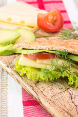 Pita pocket sandwich with cheese, avocado, tomato and lettuce.