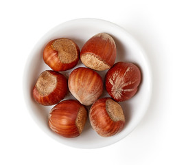 Bowl of hazelnuts isolated on white, from above