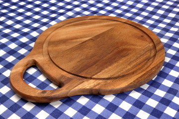 Empty Hardwood Round Cutting Board On The Blue Checkered Tablecl