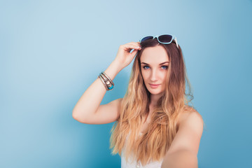 Young girl in a white T-shirt takes a selfie. Half-length portrait in a sea style.