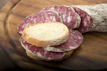 wooden cutting board with salami and bread
