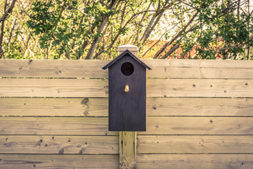 Black bird house on a fence