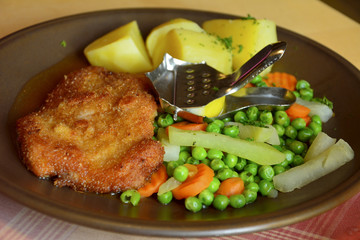 Schnitzel, pork escalope in beer gravy served with vegetables and boiled potatoes
