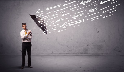 Business man standing with umbrella and drawn arrows hitting him