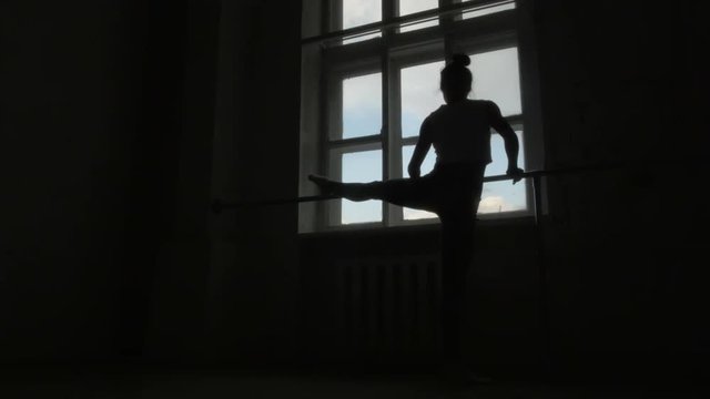 Silhouette of a Ballet Dancer Exercising at The Barre By The Window