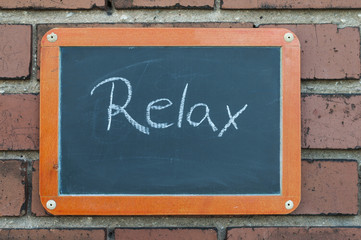 Tafel an einer Ziegelwand mit Text / Tafel an einer Ziegelwand mit Text RELAX.