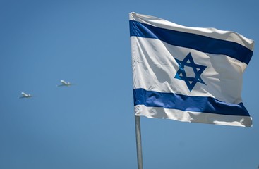 Combat planes flying over Tel Aviv seaside during the Independence day air parade with the flag of...