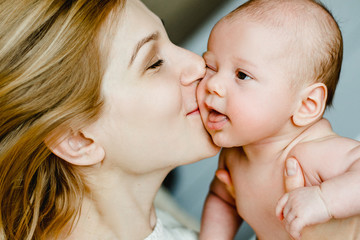 happy family mother and baby having fun playing, kissing on the bed