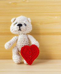 Crochet handmade doll bear with crochet heart. Art and crafts, closeup. Christmas and Valentine's day background.