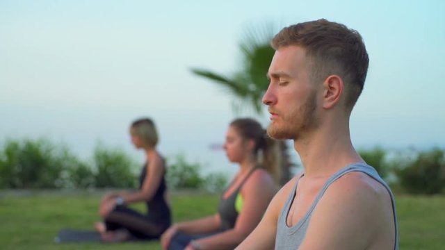 group of people doing breathing practice sitting on grass