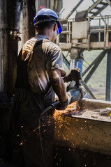  Worker grinding a metal plate.