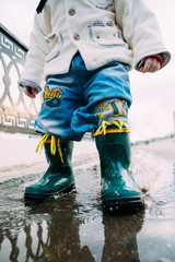 little boy walks through the puddles in the street