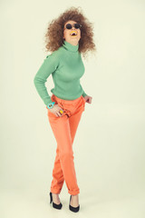 Young woman wearing retro clothes striking a pose in studio. Disco diva