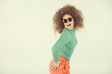 Young woman wearing retro clothes striking a pose in studio. Disco diva
