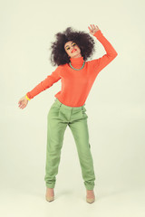 Young woman wearing retro clothes striking a pose in studio. Disco diva