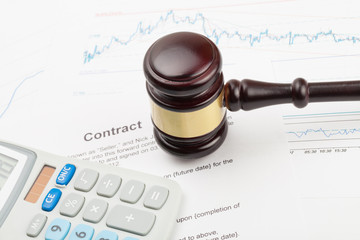 Judge's gavel and calculator above contract over - close up studio shot