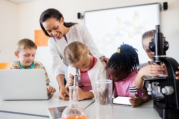 Smiling teacher helping pupils 