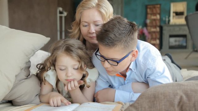 мама и старший брат помогают сделать домашнее задание маленькой девочке