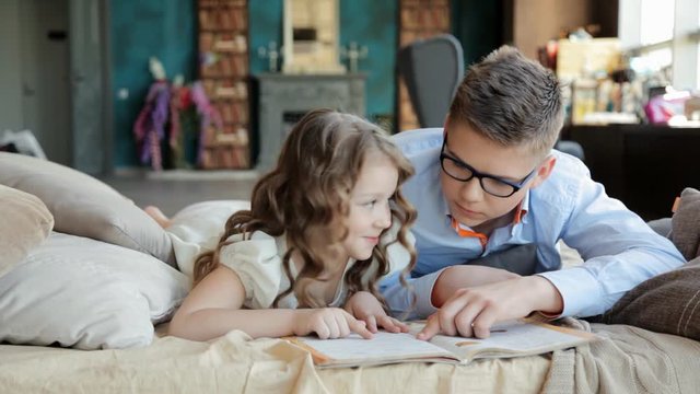 старший брат помогает сестре выполнить домашнее задание по книге